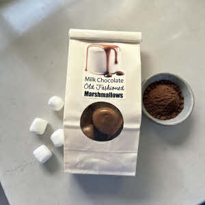package of chocolate covered marshmallows on a counter with white marshamallows and ground cocoa powder